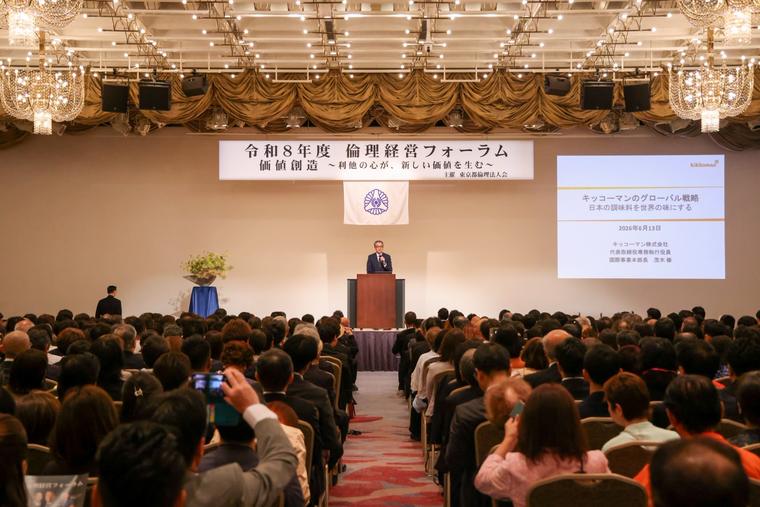 満席の会場。壇上からの開会のあいさつ。